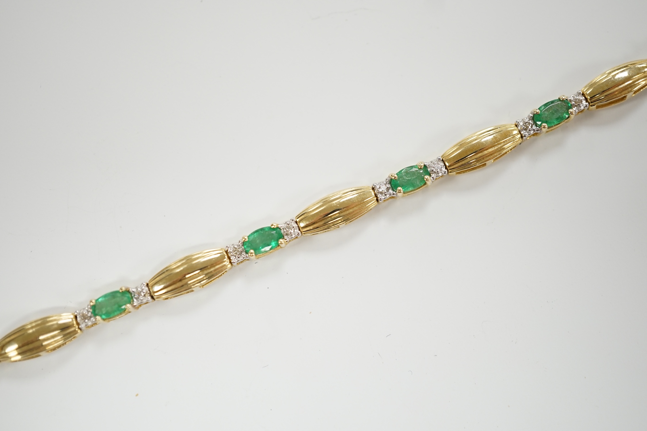 A modern yellow metal, emerald and diamond chip cluster set bracelet, 17.7cm, gross weight 7.6 grams.